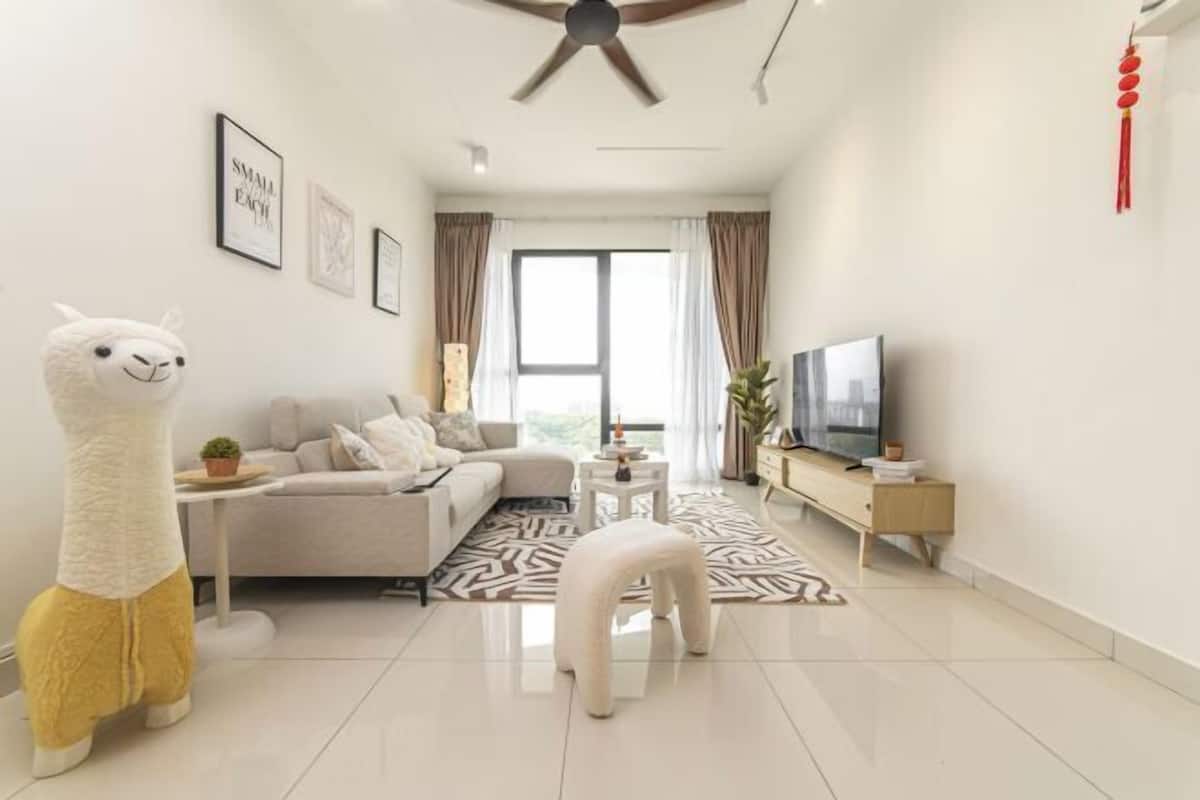 A modern living room with a sofa, a white armchair, a small table, a television, and a decorative llama statue.