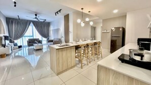 A modern kitchen with a central island, bar stools, a refrigerator, and a dining area.