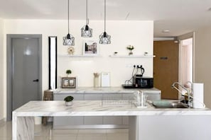 A modern kitchen with a marble countertop, pendant lights, and a built-in microwave. - Mosaic Midvalley Southkey (Johor Bahru)