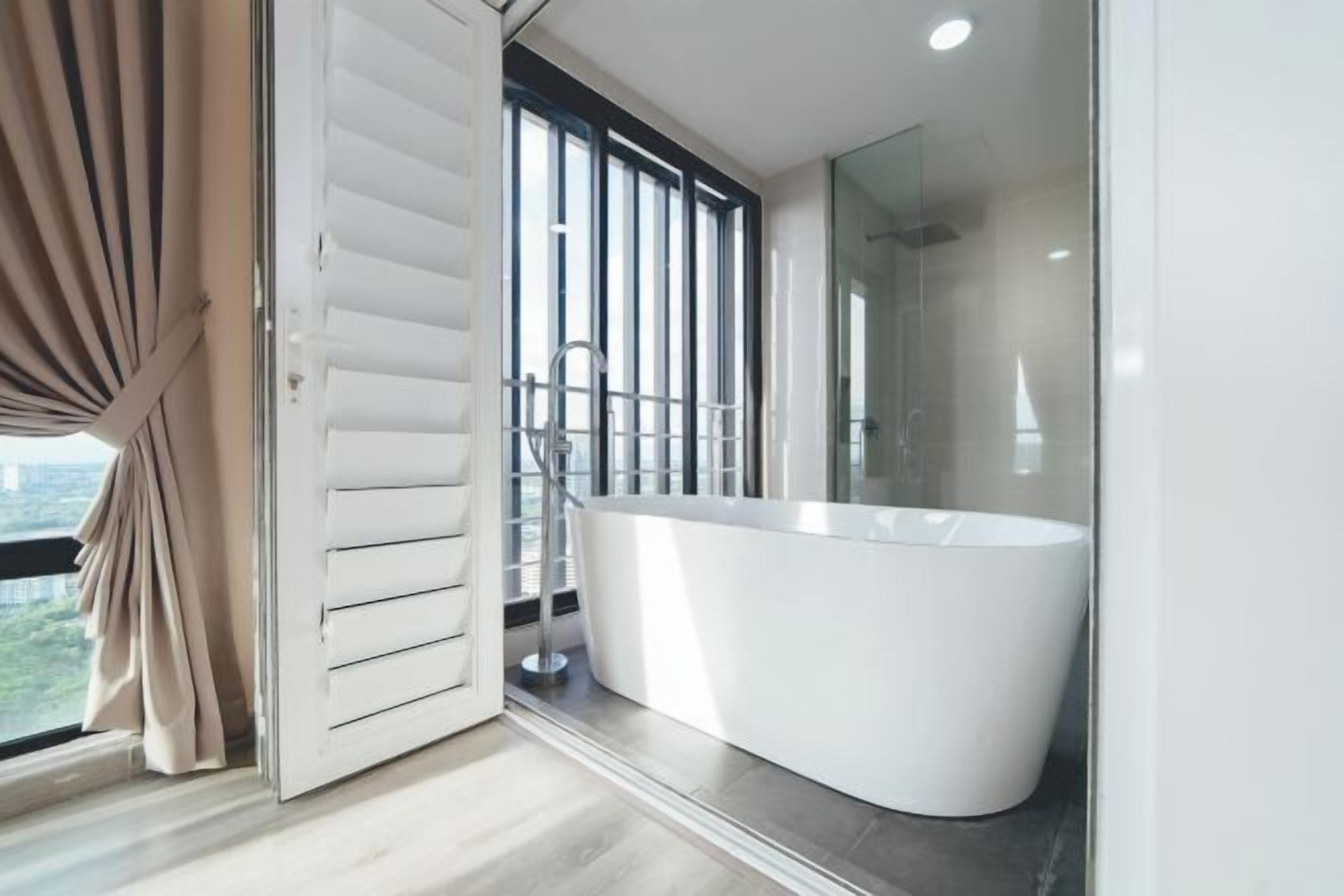 Une salle de bain moderne avec une baignoire sur pieds, une douche à parois de verre et une vue sur l’extérieur.