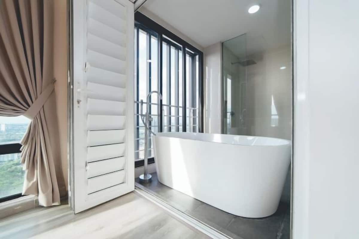A modern bathroom with a freestanding bathtub, a glass shower enclosure, and a view of the outdoors.