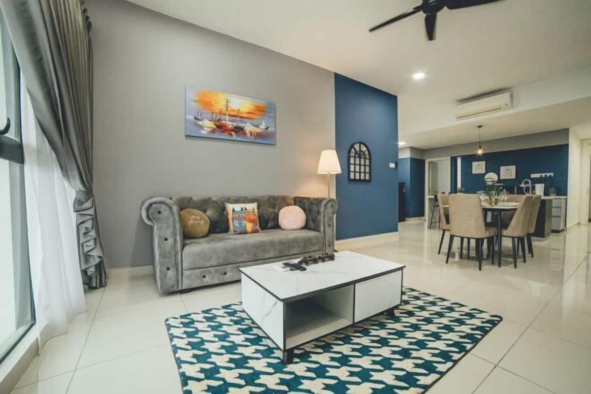 A modern living room with a grey sofa, a white coffee table, and a patterned rug.
