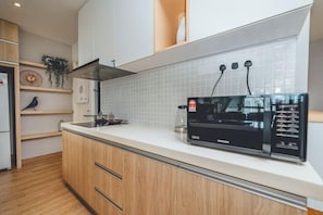 Une cuisine moderne équipée d’un four à micro-ondes encastré, d’une machine à café et d’une hotte en acier inoxydable.