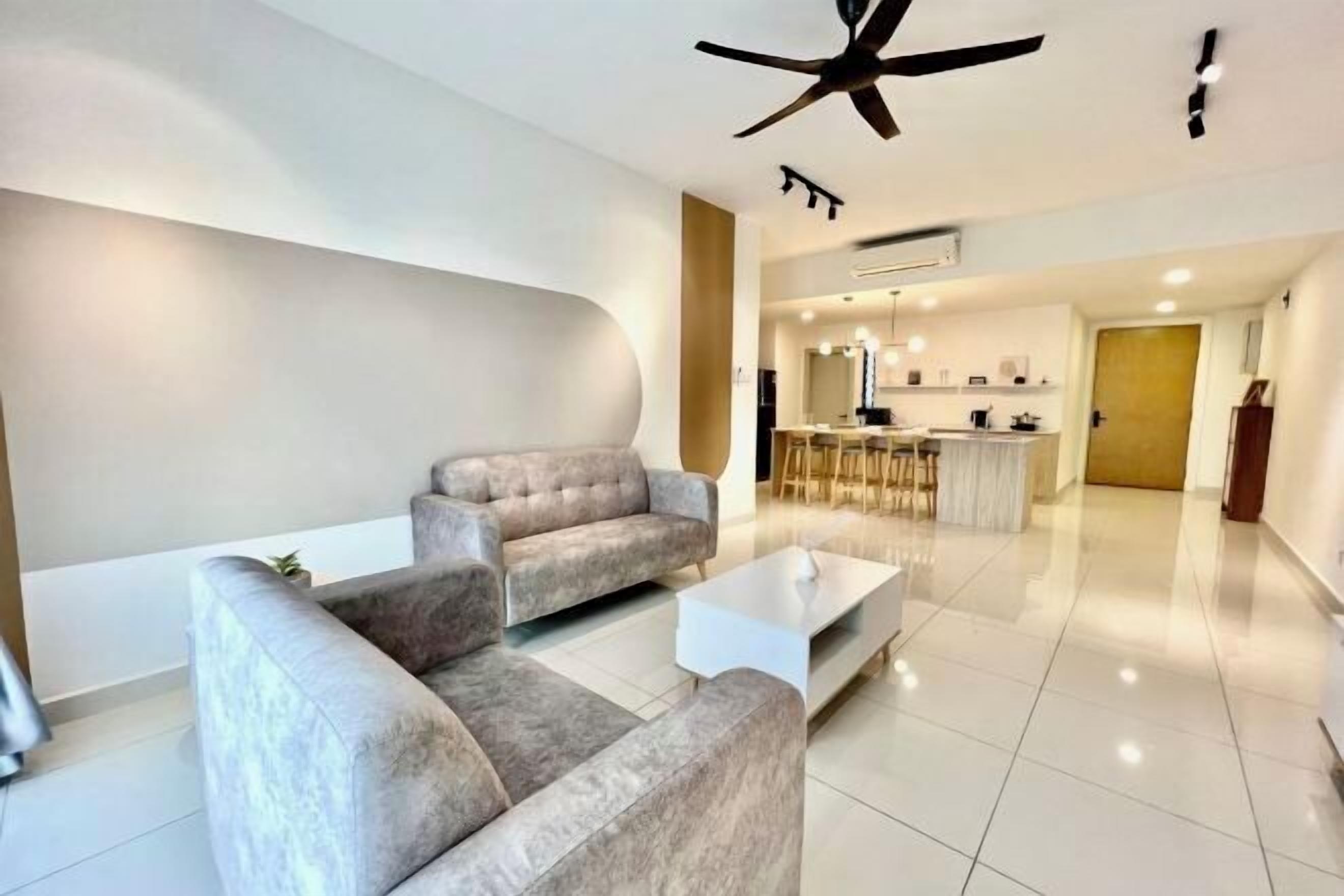 A modern living room with sofas, a coffee table, and a ceiling fan.