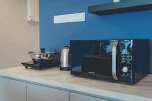 Une cuisine équipée d’un four à micro-ondes, d’une bouilloire et d’une casserole sur un plan de travail.