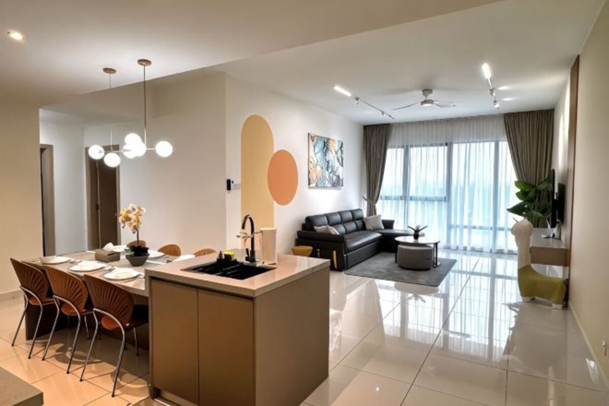 Un salon moderne avec un canapé, un coin repas comprenant des chaises et une table, et un îlot de cuisine.