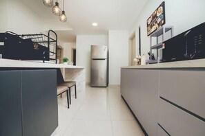 Una cocina moderna con una isla central, un refrigerador empotrado y un microondas.