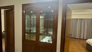 A room with a wooden wardrobe, a bed, and a window with curtains. - Mahir's Cozy Den (Dhaka)