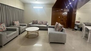 A modern living room with grey sofas, a round coffee table, and a ceiling fan. - Mahir's Cozy Den (Dhaka)