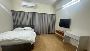 A hotel room with a bed, a desk, a television, and a curtain. - Mahir's Cozy Den (Dhaka)