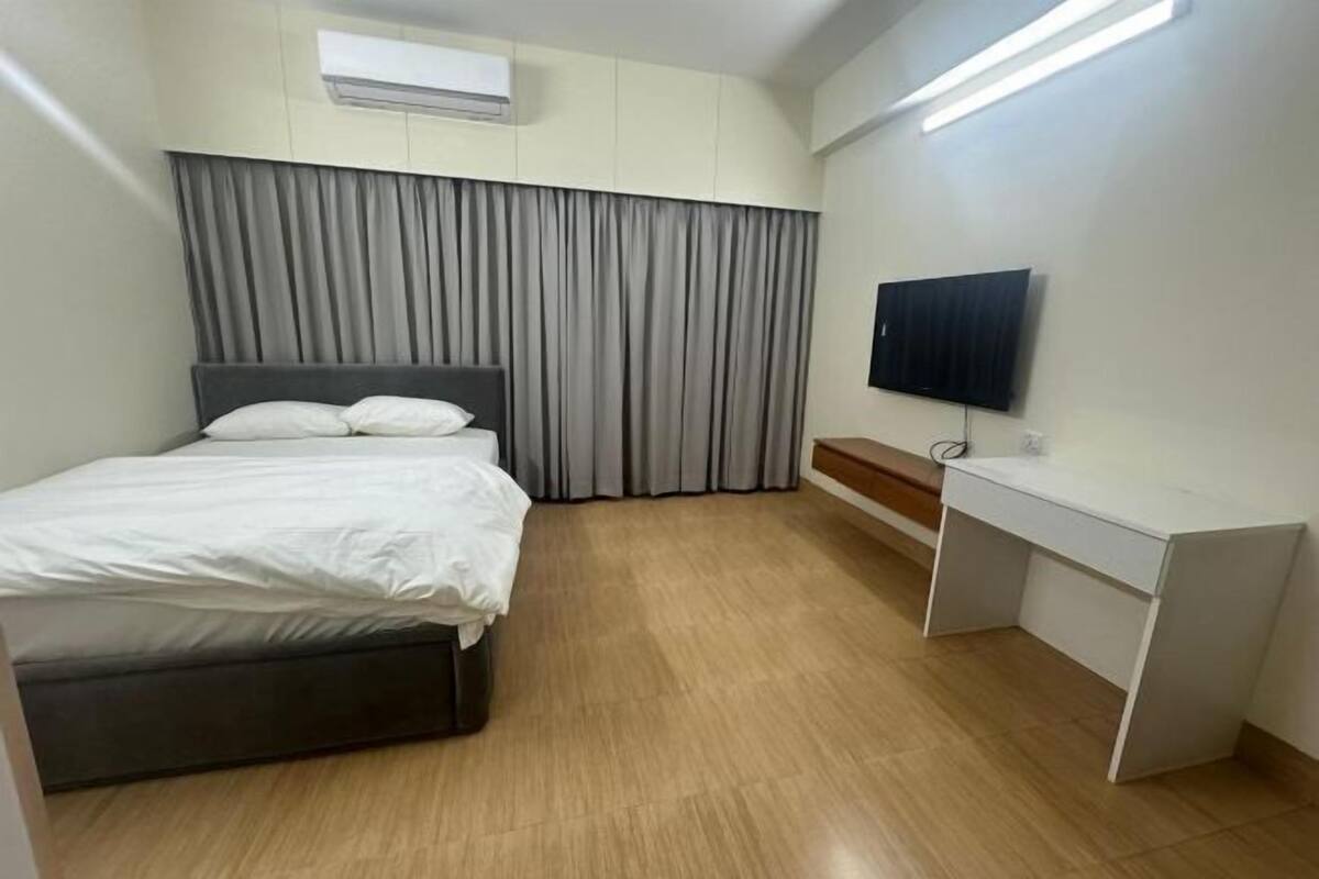 A hotel room with a bed, a desk, a television, and a curtain.