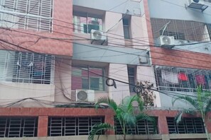 A multi-story building with external air conditioning units, visible balconies, and a gated entrance. - Mahir's Cozy Den (Dhaka)