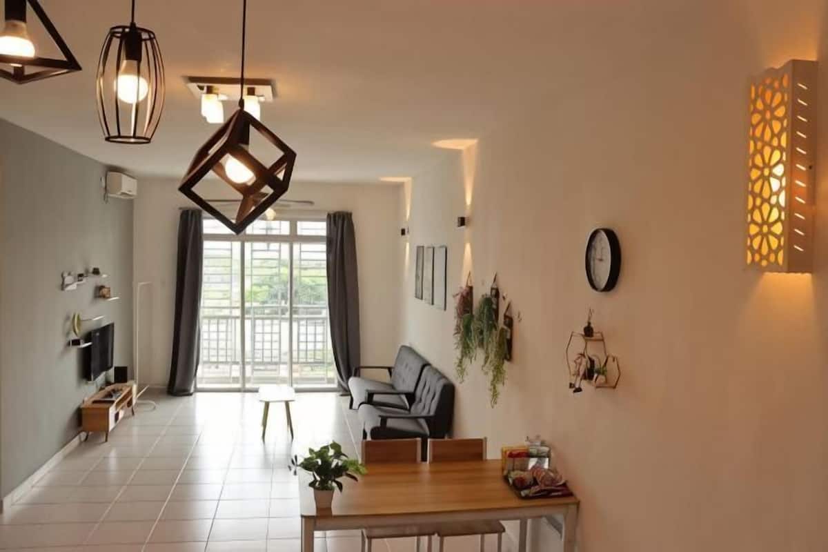 A modern dining area with a wooden table, chairs, pendant lights, and a view through a glass door to an outdoor space.
