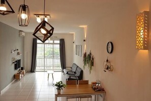 A modern dining area with a wooden table, chairs, pendant lights, and a view through a glass door to an outdoor space. - Tebrau City by Maison Inn (Tebrau)