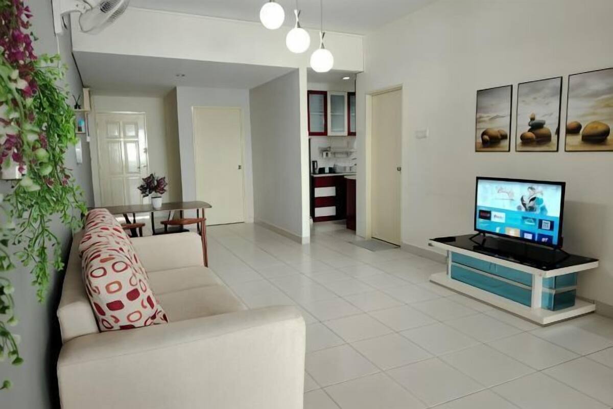 Een woonkamer met een bank, een televisie en een keuken op de achtergrond.