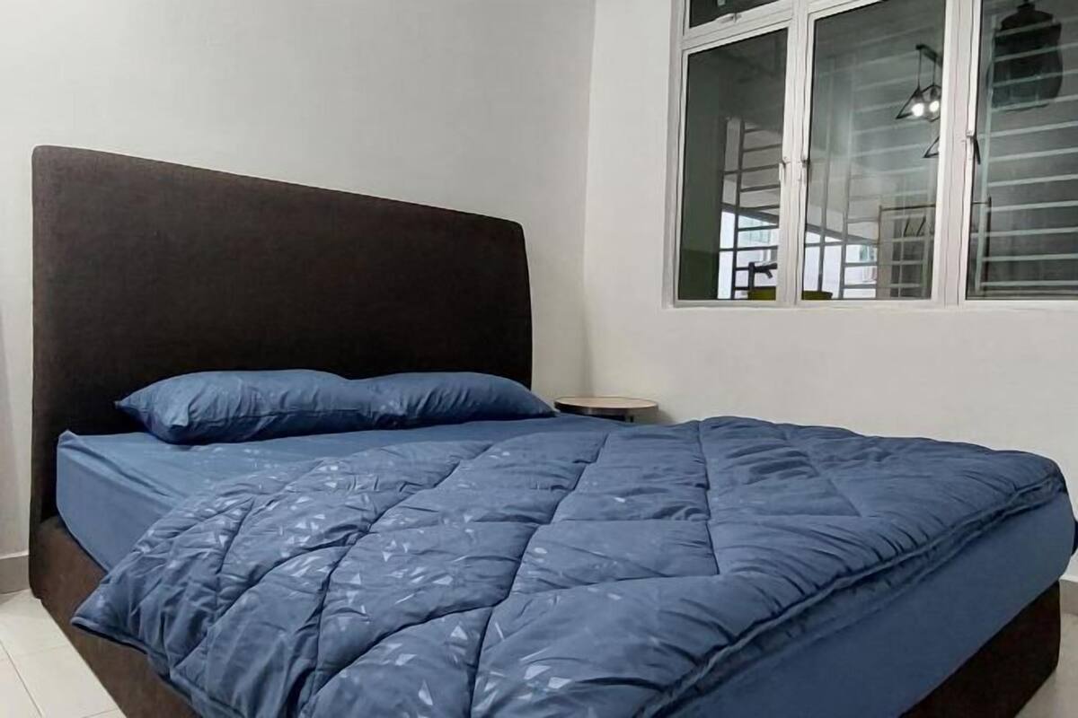 Een slaapkamer met een bed, nachtkastje en raam.