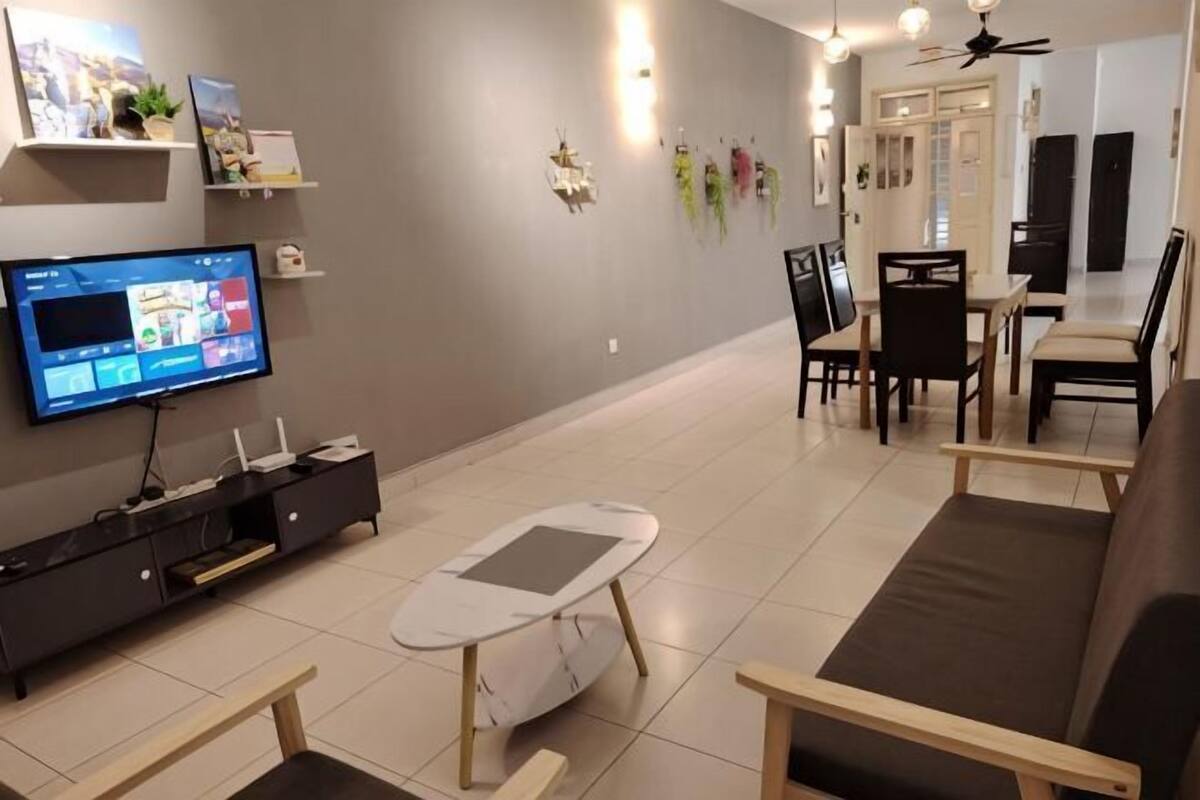 Een moderne woonkamer met een flatscreen televisie, een eethoek met stoelen en een tafel, en een plafondventilator.