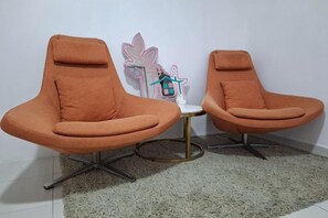 Twee oranje stoelen met een kleine ronde tafel ertussen.