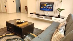 Een moderne woonkamer met een flatscreen televisie, een bank, een salontafel en een kleine plant.
