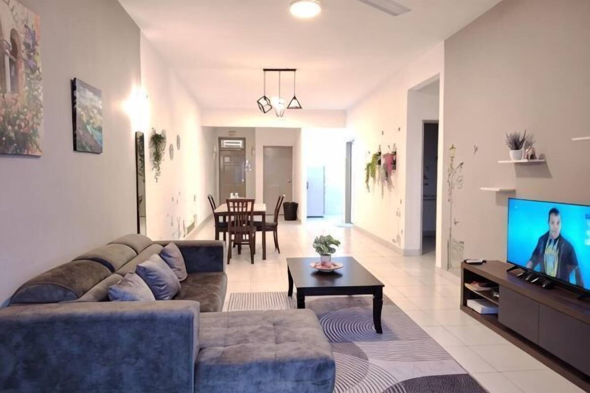 Een moderne woonkamer met een bank, salontafel, televisie en eethoek.
