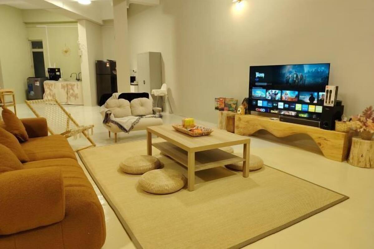 Een moderne woonkamer met een bank, salontafel, televisie en een keuken op de achtergrond.
