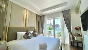 A hotel room with a large bed, a desk, and a view of the city. - Chang Luxury Villa Beach View (Phan Thiet)