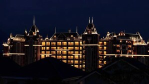 A large, illuminated hotel with multiple towers and a central building, featuring a classic architectural style. - Chang Luxury Villa Beach View (Phan Thiet)