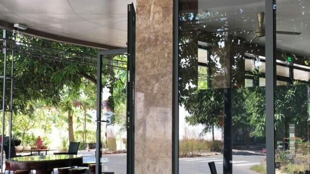 An indoor seating area with a glass wall, a marble column, and a view of the street outside.