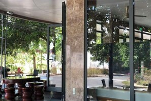 An indoor seating area with a glass wall, a marble column, and a view of the street outside.