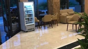 A lobby with a marble floor, a ceiling fan, a vending machine, and a seating area with chairs and a sofa.