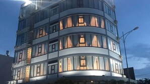A multi-story building with a curved facade, large windows, and external lighting.