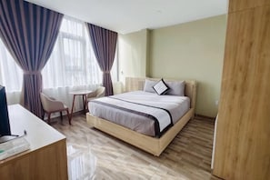 A hotel room with a bed, a desk, a chair, and a small table.