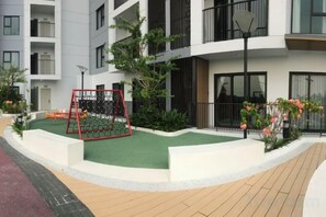 A residential building with a playground, green artificial turf, and a paved walkway. - Hoang Gia Hotel (Tan Uyen District)