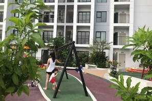 An outdoor play area with a swing set, surrounded by a building with multiple balconies. - Hoang Gia Hotel (Tan Uyen District)