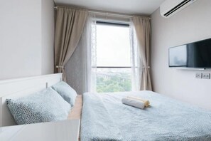 A bedroom with a bed, a TV mounted on the wall, and a window with curtains. - Nana Sukhumvit Bangkok Siam Apartment (Bangkok)