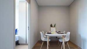 A small, modern dining area with a table and four chairs, a small plant on the table, and a door leading to another room. - Nana Sukhumvit Bangkok Siam Apartment (Bangkok)