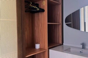 A wooden wardrobe with a hanging rack, a cup, and a mirror on the wall.