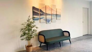 Een ontvangsthal met een bank, een potplant en kunstwerken aan de muur.
