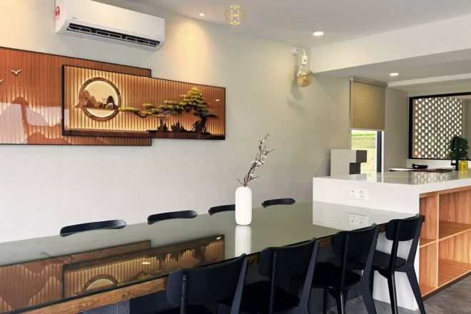 A modern dining area with a glass table, black chairs, and wooden paneling on the walls.