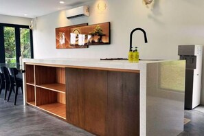 Una cocina moderna con una isla de madera, estanterías empotradas y una cafetera.