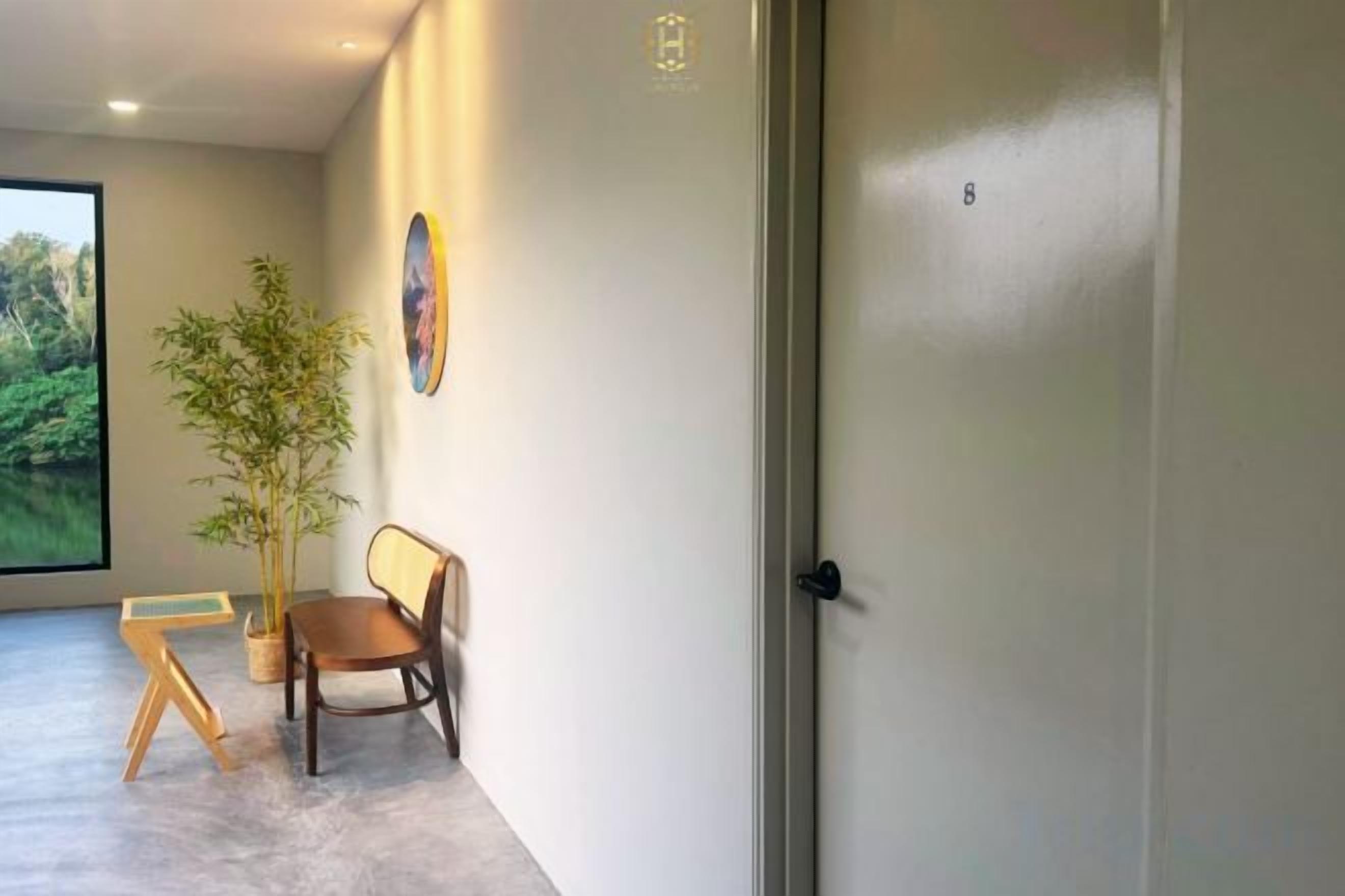 Un pasillo con una puerta, una planta en maceta, un banco de madera y un cuadro en la pared.