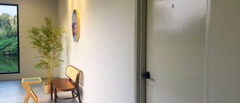 A hallway with a door, a potted plant, a wooden bench, and a framed picture on the wall.