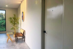 A hallway with a door, a potted plant, a wooden bench, and a framed picture on the wall. - The Luxurious 231, Lake House Villa (Pegoh)