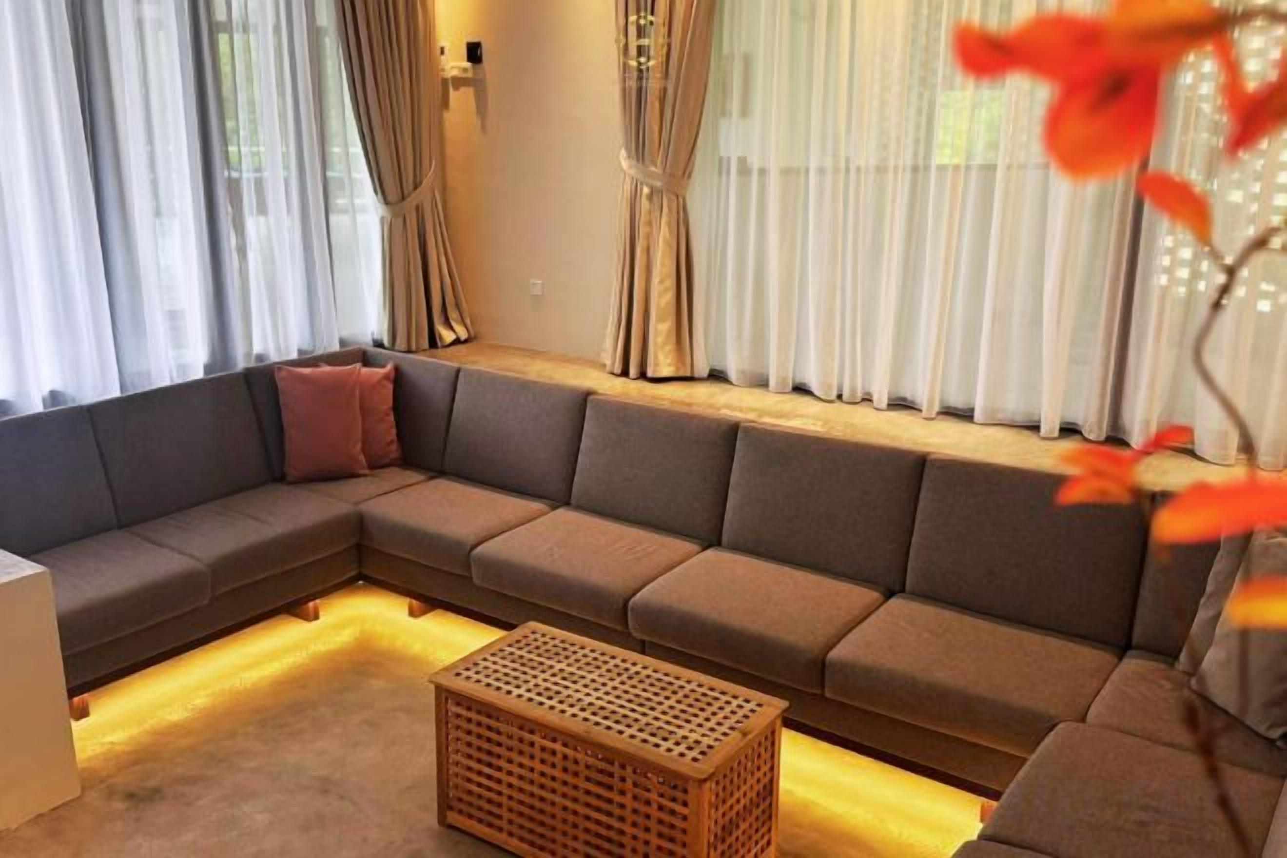 Sala de estar com sofá modular, mesa de centro de madeira e cortinas leves.