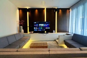 A modern living room with a flat-screen TV, two sofas, a coffee table, and a large window. - The Luxurious 231, Lake House Villa (Pegoh)