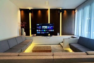 Una sala de estar moderna con un televisor de pantalla plana, dos sofás, una mesa de centro y un ventanal grande.