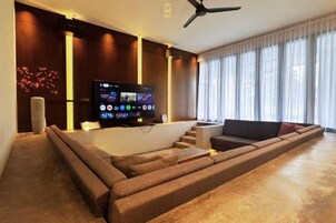 Una sala de estar moderna con un televisor de pantalla plana grande, un sofá y una mesa de centro.