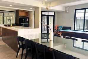 A modern kitchen with a central island, black chairs, and a pool table. - The Luxurious 231, Lake House Villa (Pegoh)