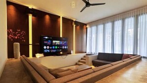 A modern living room with a large flat-screen TV, a sofa, and a staircase. - The Luxurious 231, Lake House Villa (Pegoh)