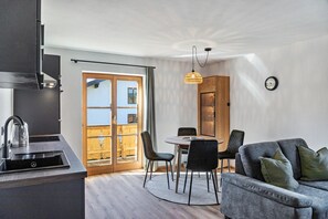 Une cuisine moderne dotée d’une cuisinière intégrée, un coin repas avec une table ronde et des chaises, et un balcon avec une balustrade en bois.